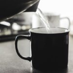 Donna che beve acqua calda al mattino, simbolo di salute e benessere per colesterolo e glicemia.