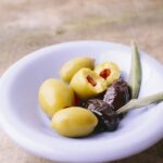 Cinque olive verdi su un piatto, simbolo di salute per il cuore e riduzione del colesterolo.